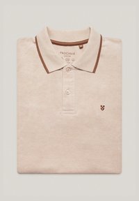 Beżowa koszulka polo z brązowym wykończeniem kołnierzyka, trzy guziki oraz małe haftowane logo. Wykonana z teksturowanej tkaniny, złożona na płasko.