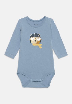 Jasnoniebieski longsleeve z nadrukiem przedstawiającym niedźwiedzia w okularach i szaliku. Posiada zapięcia na napy na dole.