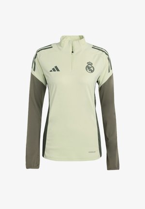Sudadera atlética verde clara con un alto cuello, cierre de cremallera en el cuello, mangas largas y detalles en verde oscuro. Presenta el logo de Adidas y el emblema del Real Madrid.