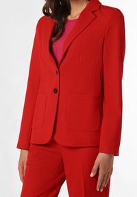 Blazer rouge au design ajusté, fermeture à un bouton, deux poches avant et revers crantés, fabriqué en tissu lisse.