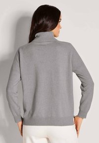 Grauer Rollkragensweater mit langen Ärmeln, gerippten Bündchen und Saum. Glatte Textur, leichter Strick und entspannter Schnitt.