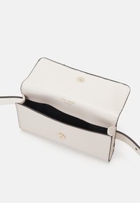 Cream-colored leather handbag with a snap closure, featuring black accents and a smooth texture. Interior displays a logo and dark lining.