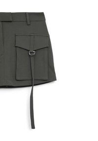 Olivgrüne Utility-Rock aus einem Stoff mit glatter Textur. Verfügt über eine Vordertasche mit Klappe, ein Metalldetail in Form eines Rings und einen Aufhängegurt.