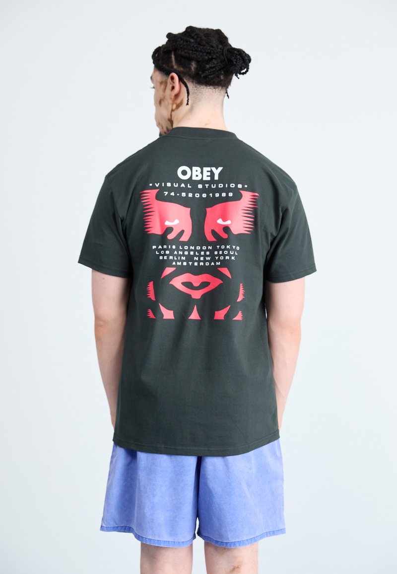 Black cotton t-shirt featuring red graphic design, "OBEY" text, and stylized faces on the back. Paired with light blue shorts.