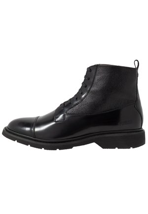Stivaletto alla caviglia in pelle nera con lacci sul davanti, pannello superiore texturizzato, linguetta sul tallone e suola spessa in gomma.