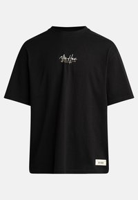 Sort oversized T-shirt med teksten "Yee Haw Untamed Outlaw" på brystet og et lille rektangulært mærke nær bunden af kanten på hvid baggrund.
