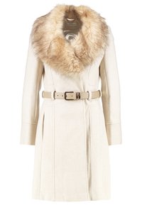 Manteau longueur genou de couleur crème avec large col en fourrure beige et ceinture assortie avec boucle dorée, manches longues et poches avant.