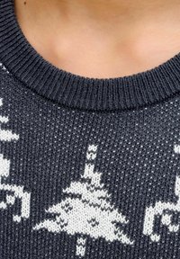 Sötét szürke kötött pulóver, bordás nyakkal, fehér geometrikus mintával, amely fákból áll, az anyagon.