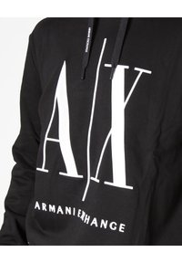 Schwarzer Kapuzenpullover mit großem weißen "A/X"-Logo und "ARMANI EXCHANGE"-Text. Verfügt über eine Kordelzugkapuze und einen weichen Stoff. 