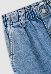 Jeans in denim azzurro chiaro con vita elastica, con cuciture gialle e un bottone argentato sul davanti, texture liscia.