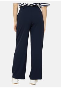Navy wide-leg trousers made from a smooth fabric, featuring a high waist and discreet side pockets for comfort and functionality.