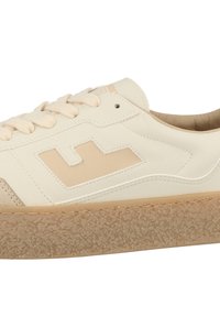 Cream-colored sneaker made of leather and suede, featuring a textured gum sole, lace-up design, and a subtle beige logo accent.