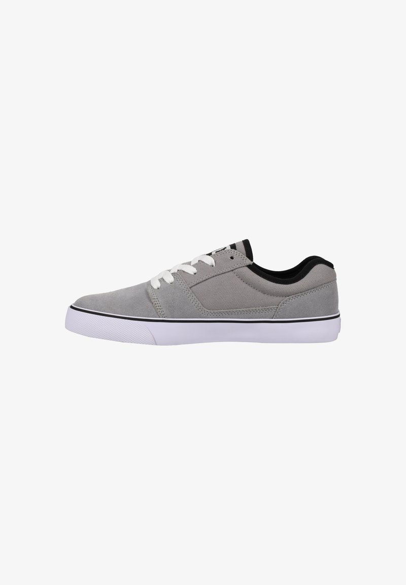 Gray canvas sneaker with white laces, black accents, and a rubber sole. Features a smooth texture and minimal detailing.