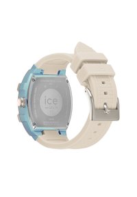 Ice Watch ima okruglo kućište od nehrđajućeg čelika s svijetloplavim akcentom, kremastom silikonskom narukvicom i metalnom kopčom, ističući minimalistički dizajn.