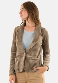 Giacca in corduroy marrone con colletto a scialle, due tasche anteriori e chiusura con bottone. Presenta maniche lunghe e una finitura texture.