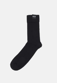 Schwarze gerippte Socke mit umgeschlagenem Bündchen, das ein kleines Logotag trägt. Das Material wirkt weich und hat eine gleichmäßige Textur.