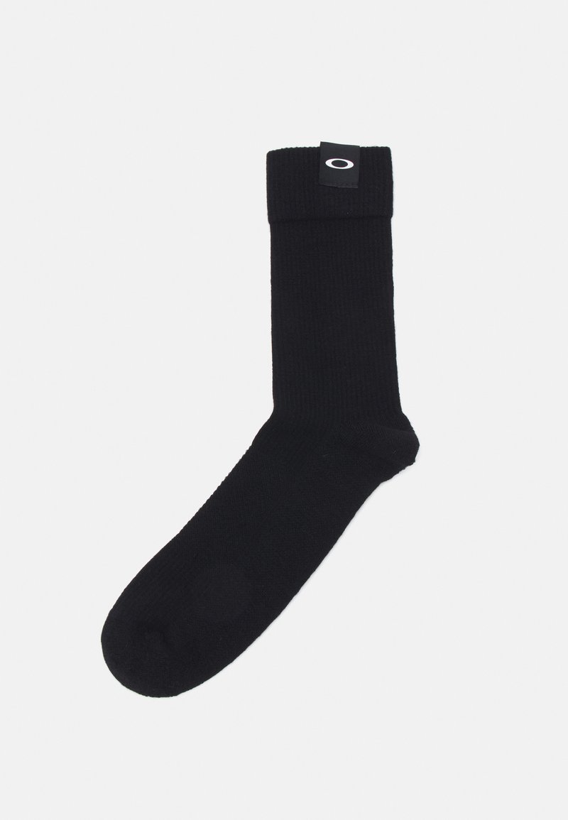 Schwarze gerippte Socke mit umgeschlagenem Bündchen, das ein kleines Logotag trägt. Das Material wirkt weich und hat eine gleichmäßige Textur.