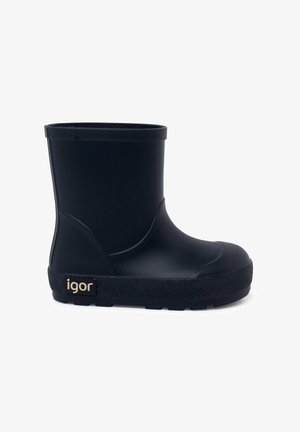 Botas de goma negras impermeables con suela plana, punta redondeada y textura suave. Presenta una etiqueta dorada de la marca en el lado.