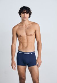 Marineblå Nike boxer briefs med en hvit logo på linningen, laget av mykt, elastisk materiale, med tettsittende passform og dekker midt på låret.