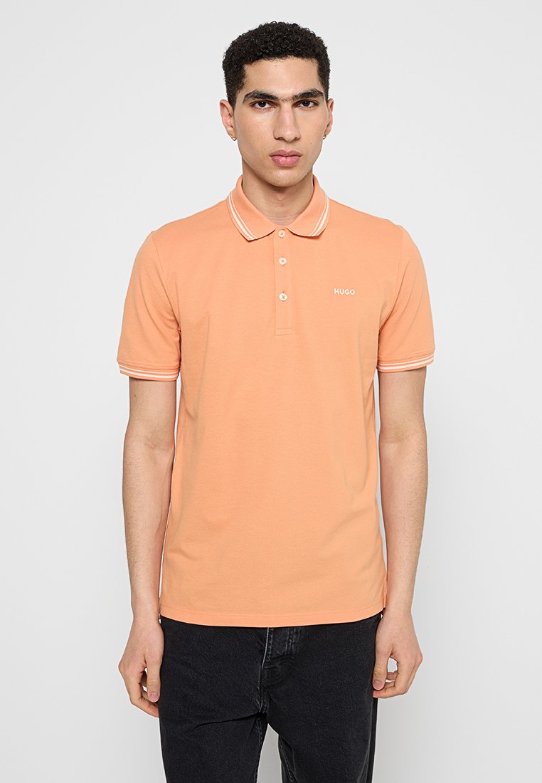 Koszulka polo w jasnopomarańczowej bawełnie z zapięciem na trzy guziki, kontrastowymi białymi paskami kołnierzyka oraz małym logo na piersi.