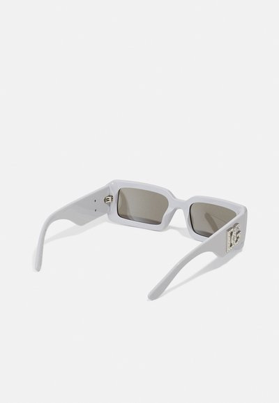 Lunettes de soleil grises avec des lentilles rectangulaires et une monture épaisse. Accentuée d'un logo métallique décoratif sur le côté droit.