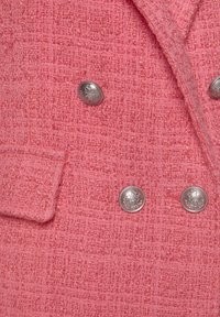 Růžový texturovaný blazer s dvoubarevným designem, dvěma stříbrnými knoflíky a kapsou na levém prsu.