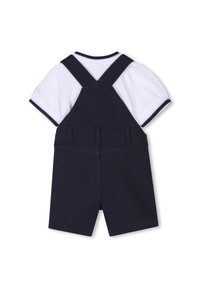 Navy blue overall shorts with adjustable straps and a white short-sleeve shirt, featuring a navy trim on the collar and sleeves.