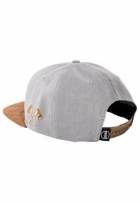 Gorra gris con visera de ante marrón, con hachas cruzadas bordadas en dorado en la parte posterior. Correa ajustable con detalle del logo.