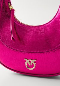Borsa a tracolla in pelle di un vivace rosa fucsia, con una finitura testurizzata, hardware dorato e un'icona del logo in rilievo. Chiusura con zip lungo il bordo superiore.