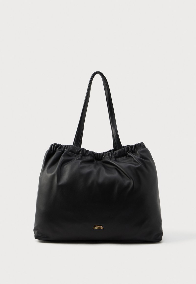 Μαύρη δερμάτινη τσάντα tote με μαζεμένο επάνω μέρος και λείες υφές, διαθέτοντας δύο ανθεκτικά χερούλια και ένα μικρό χρυσό λογότυπο μπροστά.