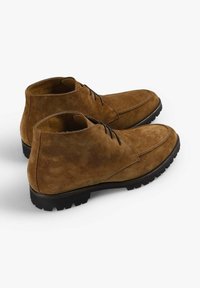 Brune ruskindsankelstøvler med en glat tekstur, der har sorte snørebånd og en robust gummisål for godt greb. Klassisk, minimalistisk design.