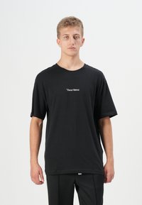 Tricou negru din bumbac cu mâneci scurte și guler rotund. Textul alb centrat spune "Tower Bridge." Textură netedă, croi lejer.