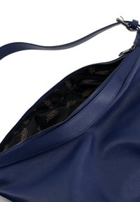 Blaue Lederhandtasche mit strukturierter Oberfläche und Reißverschlussöffnung. Das Innere ist mit einem schwarzen Futter mit Logo-Muster ausgestattet. Verstellbarer Schulterriemen inklusive.