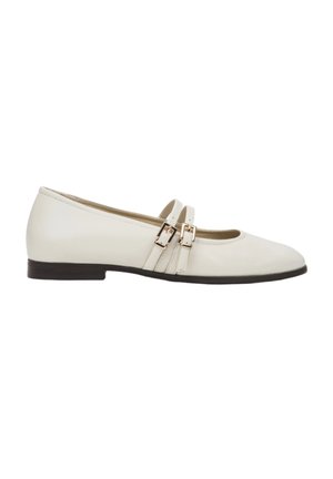White patent leather flats with a rounded toe, featuring two decorative straps with rectangular gold buckles, and a low, textured brown sole.