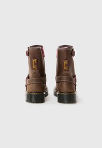 Brown leather ankle boots with pink accents, sturdy buckle straps, and a textured black sole. Stitching details visible on the sides.