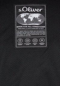 s.Oliver žaketes etiķete ar pasaules karti, uz kuras rakstīts "Izstrādāts visiem apstākļiem" un iezīmētas īpašības, piemēram, darbs un atpūta, jebkura gadījuma, komforts un inovatīvas auduma tehnoloģijas.