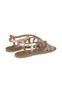 Strappy sandalen met een metallic roségouden afwerking, voorzien van kleurrijke edelsteenaccenten en gevlochten bandjes. Platte zool met stiksels.