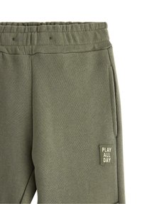 Olivgrüne Jogginghose mit elastischem Bund, Seitentaschen und einem kleinen Aufnäher mit der Aufschrift "PLAY ALL DAY" nahe der Tasche.