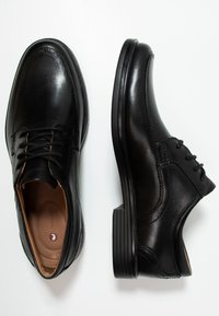 Scarpe da uomo in pelle nera con punta arrotondata, chiusura con lacci, cuciture sottili e suola in gomma testurizzata per una buona aderenza.