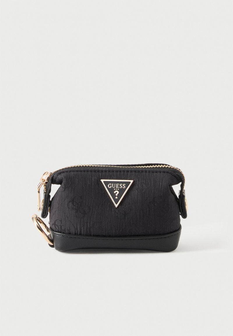 Petite pochette noire de la marque Guess avec fermeture éclair dorée et porte-clés sur fond clair uni.