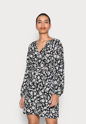 Vestido preto floral com padrões brancos, decote em V, mangas longas, cintura ajustada. O tecido parece leve com uma textura suave.