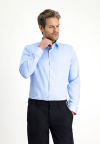 Lichtblauw overhemd met lange mouwen en een button-down kraag. Kenmerkt zich door een gladde stoftextuur en contrasterende knopen. Draagt bij donkere broek.