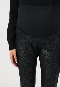 Svarta gravidleggings med en glänsande djurtryckdesign, med en mjuk och elastisk midjeband för komfort.