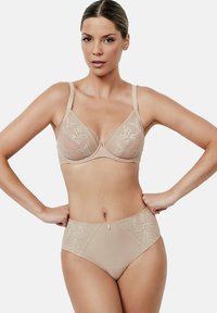 Beige kanten beha met doorschijnende panelen en verstelbare banden, gecombineerd met bijpassende hoge slipjes met bloemenkant accenten.
