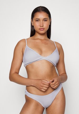 Conjunto de bikini às riscas, featuring um top triangular com alças finas e uma parte de baixo de corte baixo, ambos em branco com riscas azul-marinho. Textura suave.