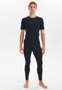 Sort kortærmet bluse og lange leggings lavet af strækbart stof. Blusen har en rund hals; begge dele har en glat tekstur.