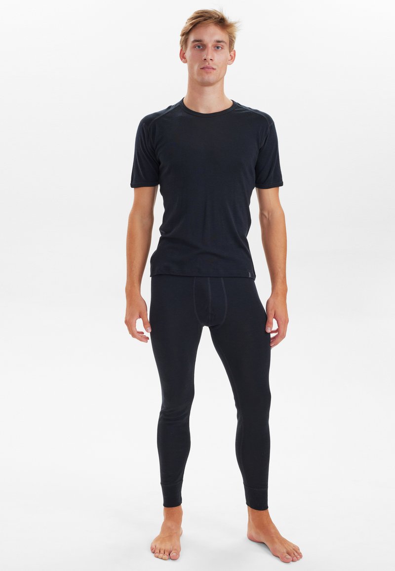 Sort kortærmet bluse og lange leggings lavet af strækbart stof. Blusen har en rund hals; begge dele har en glat tekstur.