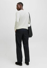 Pull rayé blanc, pantalon noir et sac noir. Texture lisse, design ajusté et coupe décontractée avec poches visibles.