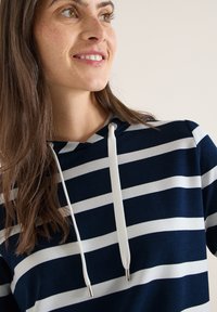 Sweat à capuche bleu marine et blanc à rayures avec une capuche à cordon et des accents argentés, fabriqué en tissu doux, offrant une coupe décontractée et un style casual.