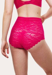 Högtalande fuchsias lace-underkläder med blommotiv, vågiga kanter och genomskinlig textur, med medelhög täckning.